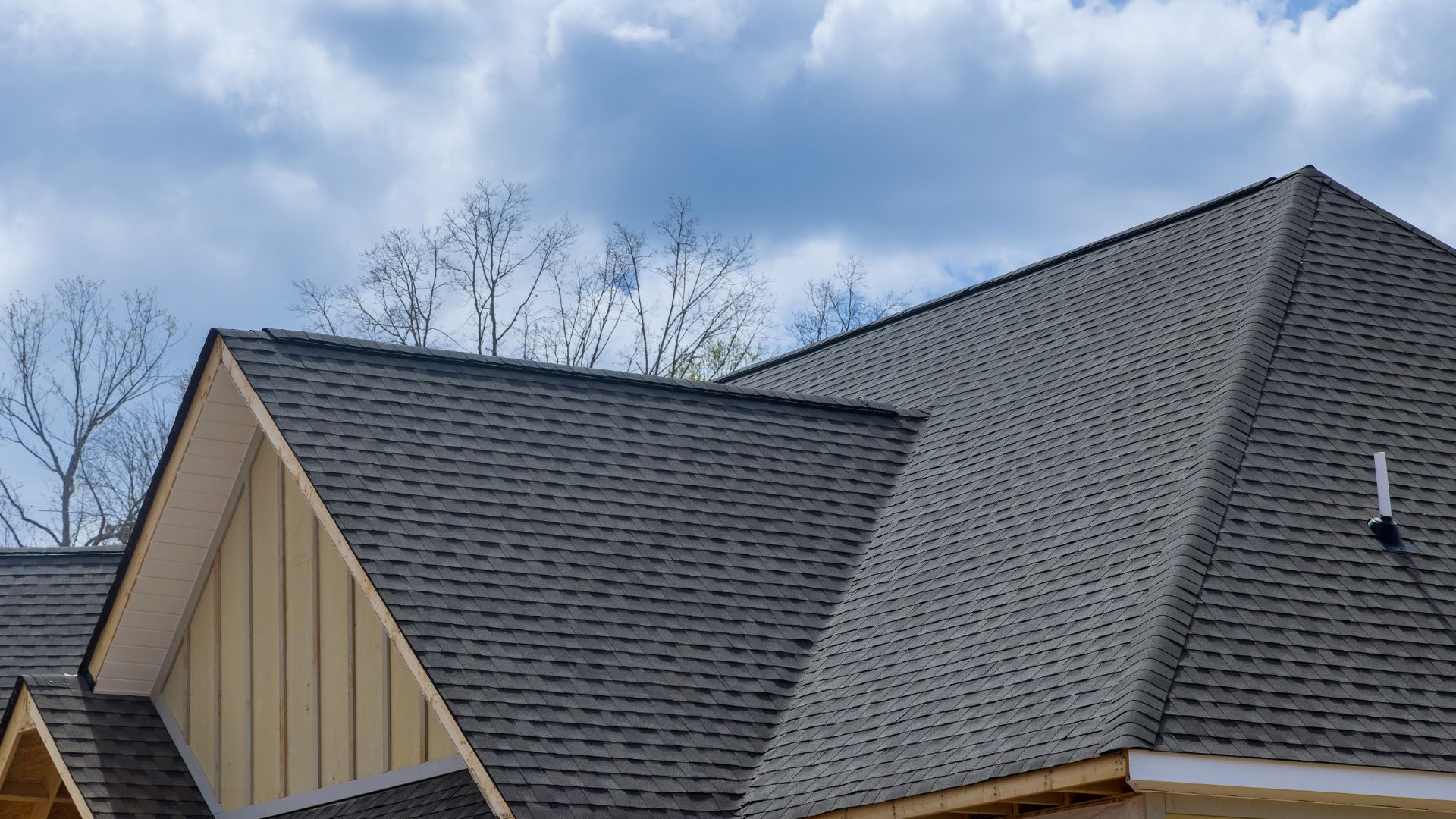 Gray asphalt shingle roof with multiple angles against blue sky