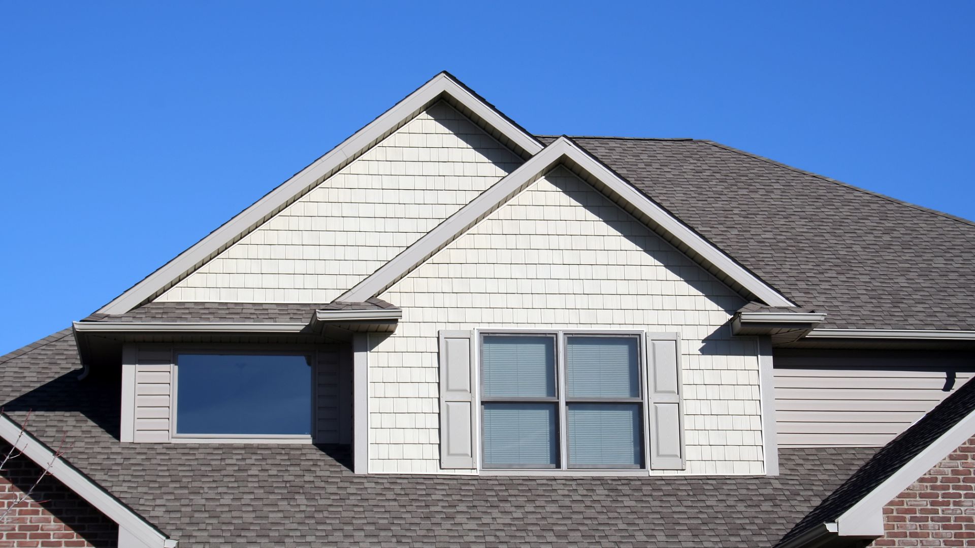 White and gray house with two windows and gray shingle roof