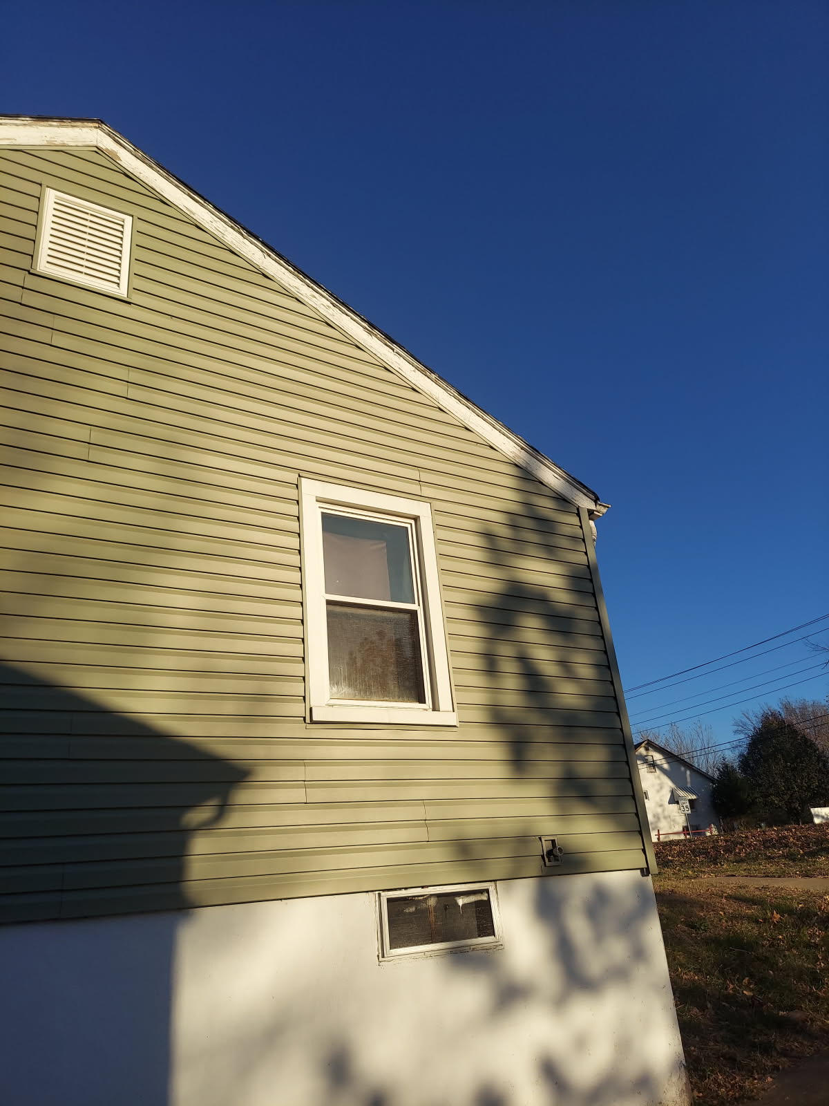 Olive green house with two windows against clear blue sky