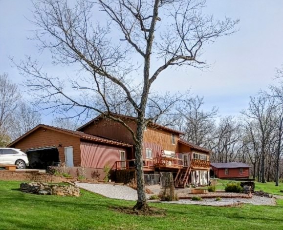 Wooden house with bare trees and green lawn in rural setting