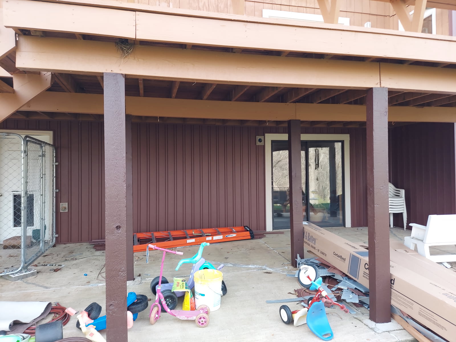 Cluttered garage or workshop with children's toys, stretcher, and construction materials